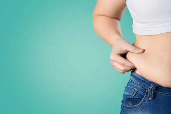 Image of woman pinching her love handles to show weight gain Ampthill